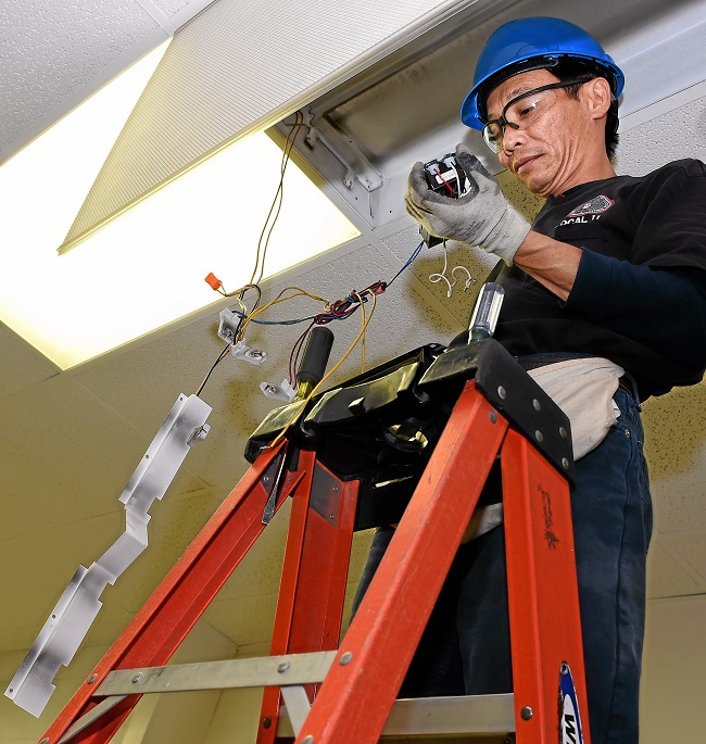 Duy Ha installs new lights, ballast system, and motion sensors at La Puente High School .