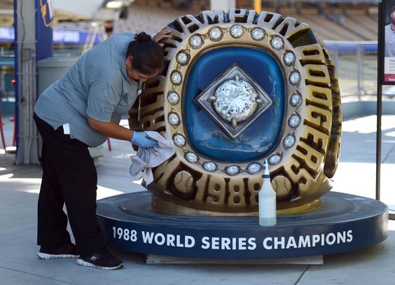 Elana Morales polishes the giant Tommy Lasorda replica championship ring at Dodger Stadium before the start of Game 4 of the National League Championship Series. (Stephen Carr/Staff photographer)