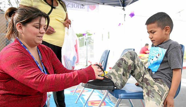 Katherine Rodriguez helps Edgar Hernandez  put on his new shoes.  (Photo Correspondent by Shilah Montiel/ 