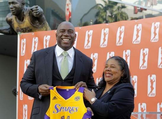 Former Los Angeles Laker Magic Johnson is joined by WNBA president Laurel Richie in front of Staples Center on Feb. 5, 2014, to announce that he is part of a group buying the Los Angeles Sparks of the WNBA. (AP Photo/Nick Ut)