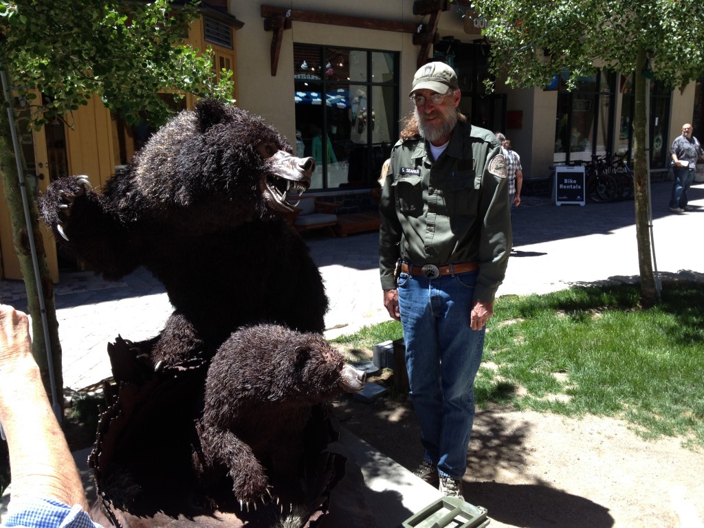 Mammoth Wildlife Manager poses near bear statue in Mammoth Village. Photo by Richard Irwin