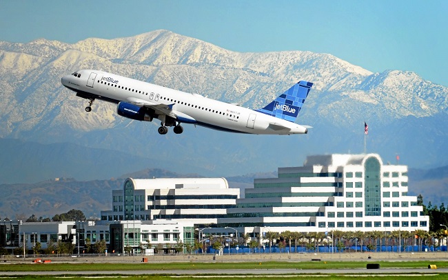 With the rains behind us, for now, a JetBlue takes off from Long Beach Airport with blue skies, snow caped mountains and the Boeing Co. office buildings behind it on a sunny morning.