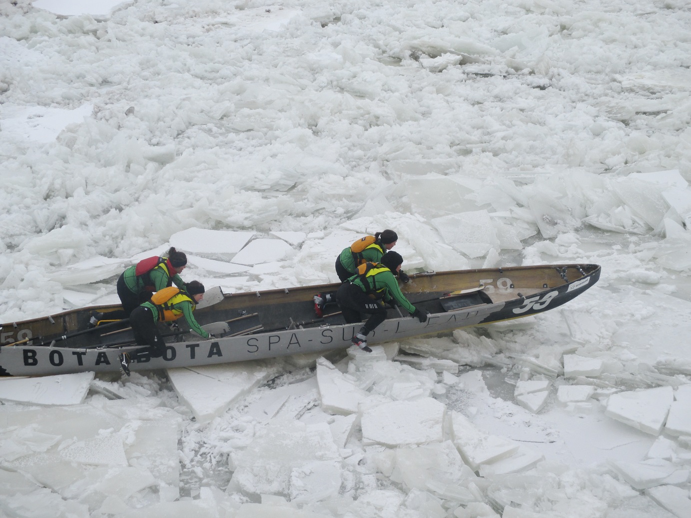 A crew in the elite female class work to get their canoe across the ice. (Photo by Marlene Greer)