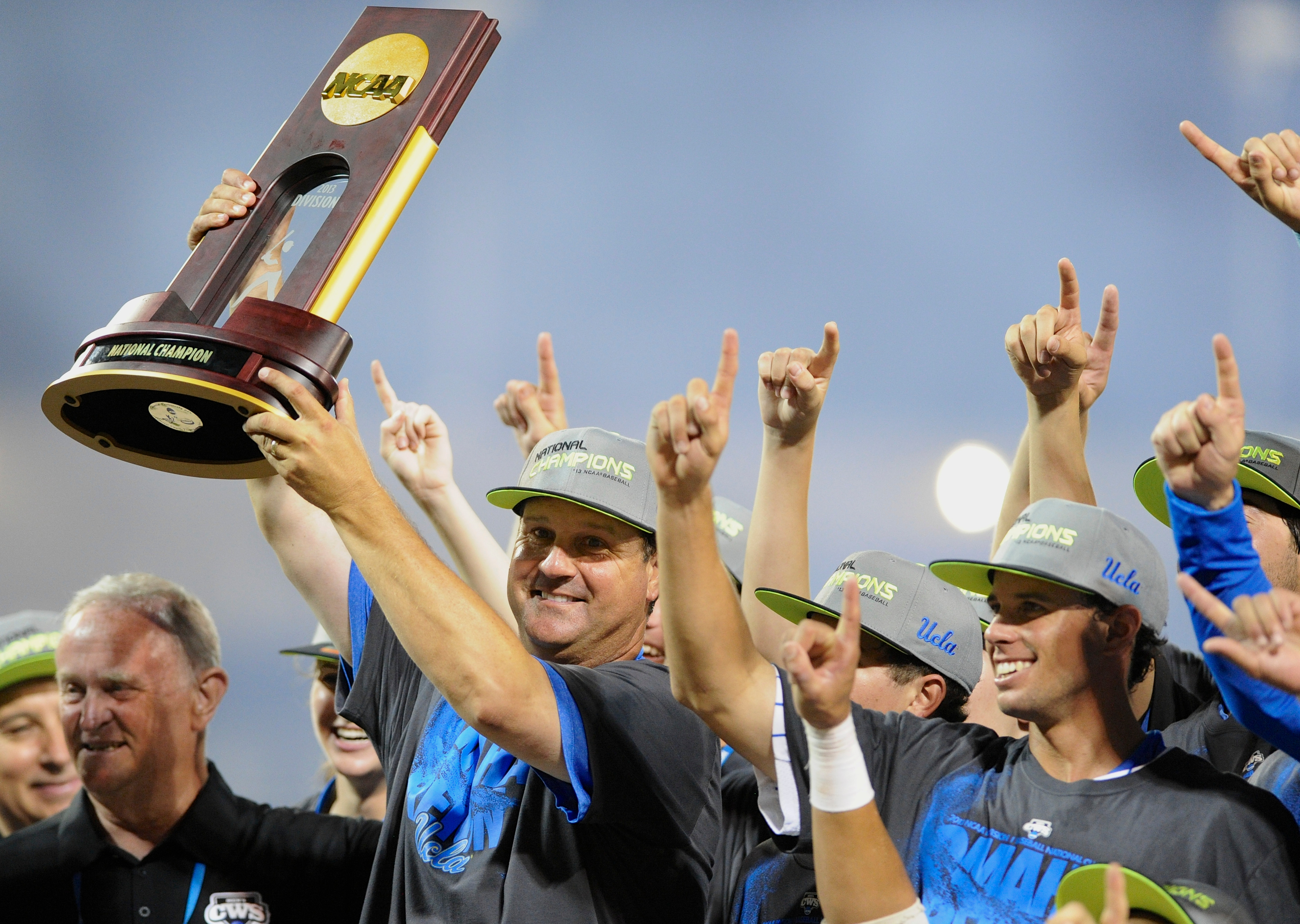 UCLA coach John Savage is surrounded by players as he hoists the College World Series championship trophy on June 25, 2013. (Eric Francis/AP)